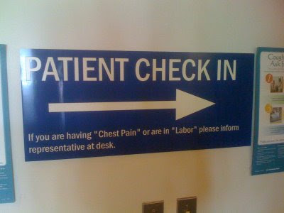 Blue sign reading PATIENT CHECK IN If you are having 'Chest Pain' or are in 'Labor' please inform representative at desk.