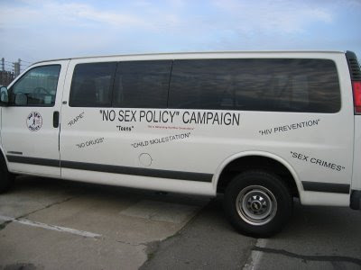 White van with many phrases in quotes on the side. Most prominent is 'NO SEX POLICY' CAMPAIGN