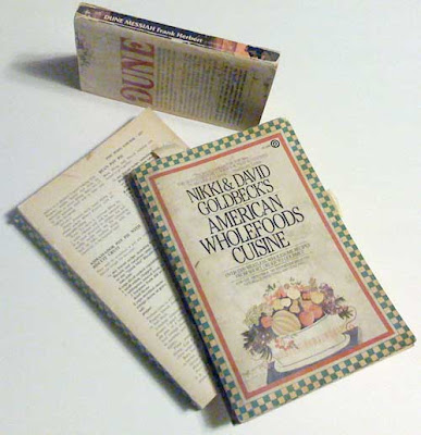 Photo of a large paperback broken in half through wear and a smaller paperback with dog-eared covers