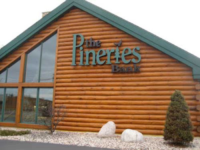 Log building with big windows and a sign that reads The Pineries Bank
