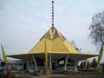 1960s circular building with yellow pointed roof and tower at top