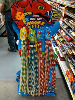 Cardbord point of purchase display of a giant red snake, holding multiple striped gummi snakes, with the headline BIG FAT HISSEE FIT
