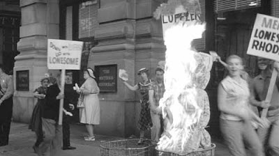 People with picket signs burning a mattress in a trash can