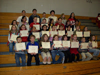 Noel Elementary School's A honor roll students sitting on the bleachers in the gymnasium holding their honor roll certificates