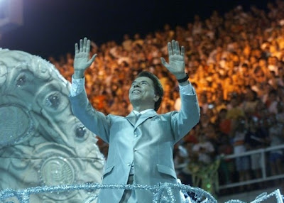 http://4.bp.blogspot.com/_ksD_g04x3Gk/TQYfa-c6giI/AAAAAAAAJJQ/MaAA_Dhedhg/s1600/silvio-santos-desfila-pela-tradicao-em-ano-que-a-escola-homenageia-o-dono-do-sbt-com-o-enredo-o-homem-do-bau-hoje-e-domingo-e-alegria-vamos-sorrir-e-cantar-2001-1292027320287_560x400.jpg