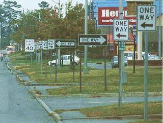 picture of one-way signs pointing in different directions along a street