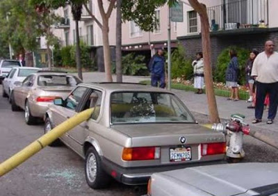 photo of a car parked in front of a hydrant with fire hose running through it
