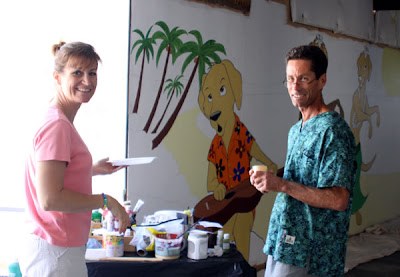 GDB employees Teri Balestrieri and Mark Bollinger stand in front of the partially complete mural