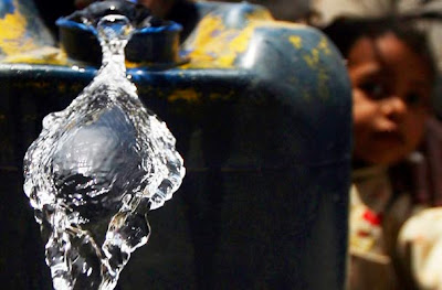 A girl fills containers with water from another at Dar El Salam, Cairo.