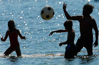 People play with a ball as they take a dip on a sunny spring day at Berlin's Wannsee lido
