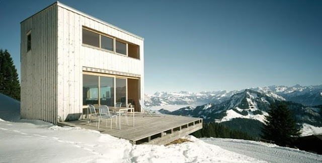 Vista en perspectiva de la moderna construcción con un deck de madera a modo de terraza Chalet suizo de estilo Contemporáneo en Suiza