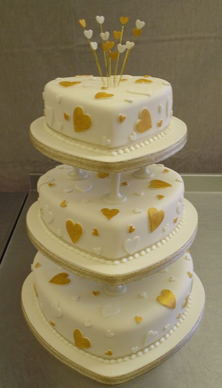 Three seperate tier white heart shaped cake with little white and gold 