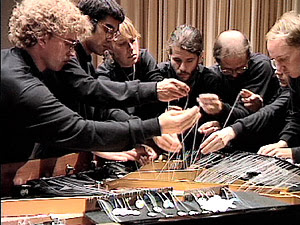 10 musicians armed with fishing line, Popsicle sticks, and plumbing tape to play the bowed piano. 10 musicians armed with fishing line, Popsicle sticks, and plumbing tape to play the bowed piano.