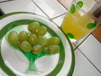 Plastic bowl with grapes inside next to glass of juice