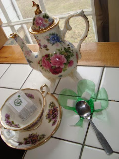 Shamrock bowl next to floral patterned teacup and teapot with bowl holding spoon and sugar cubes