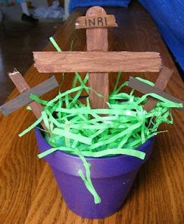Purple pot with fake grass containing three wooden crosses