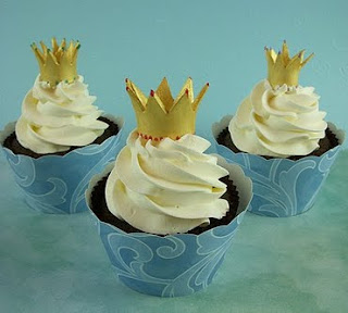 Chocolate cupcakes with white frosting and crown topper in blue wrappers