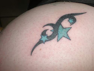 Foto em close de tattoo de estrelas prenchidas com um verde meio azulado ornamentada por motivo tribal
