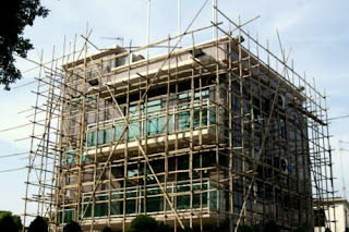 Bamboo scaffolding around a small house in Hong Kong's New Territories. Image of a small house in Hong Kong surrounded with bamboo scaffolding for the workers to walk on.