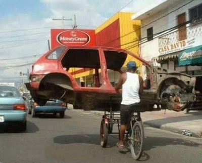 funny man carrying car on bike