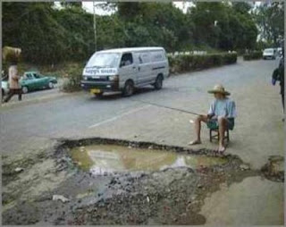 funny fishing photos man in road trying to catch fish in pot hole or puddle