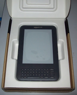 Primeira visão do Kindle. A parte branca da embalagem é papelão, não plástico. Clique para ampliar.