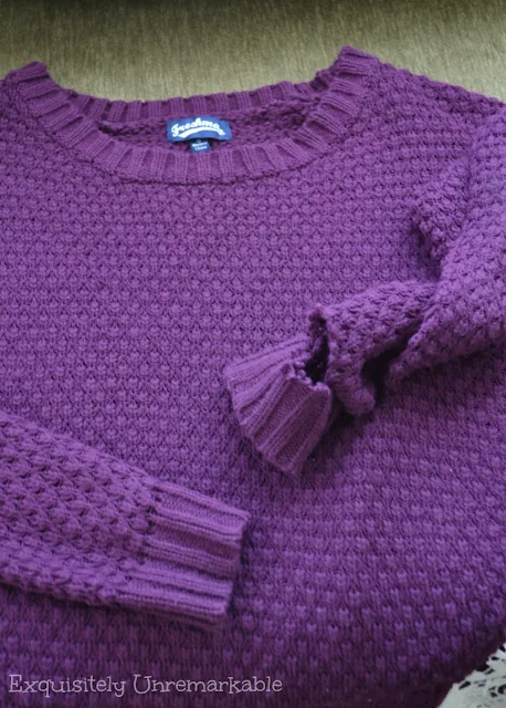 Purple sweater with torn sleeve cuff