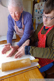 image of grandmother showing grandson how to shape lefse before rolling out the dough