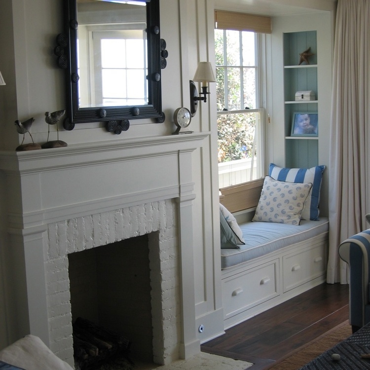 Charming traditional decor in living room with fireplace and window seat of Malibu beach house by Giannetti Home