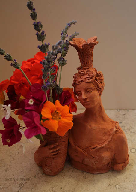 Lady with Plumes, Sarah Myers. Sculpture. lady, plumes, basket, sarah, myers, art, arte, artist, terracotta, sculpture, vase, escultura, skulptur, flowers, bouquet, arrangement, beautiful, feathers, woman, figurative, decor, decorative, contemporary, modern, red, earthenware, clay, face, eyes, cornucopia, lavender, nasturtiums, jasmine, bougainvillea, spring, printemps, primavera, handmade, bright, pink, yellow, orange, flores