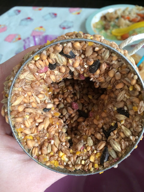 The can covered in bird seed and peanut butter, with seed also inside the can