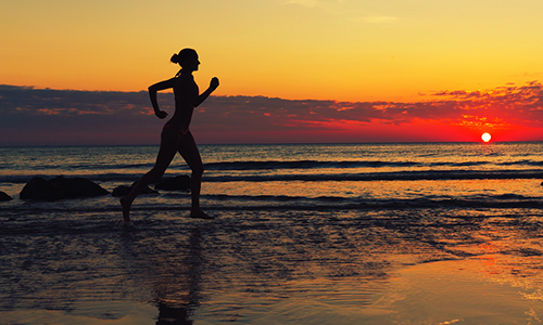 Girl running on beach in an effort to attain set goals. 