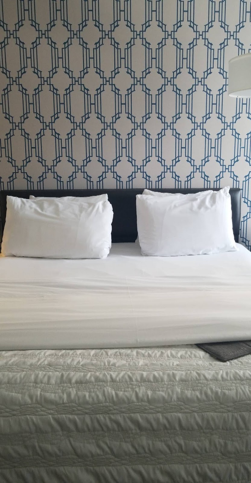 Guest room with hexagon-patterned wall paper and a plush king bed