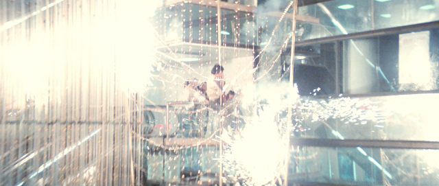 Jackie Chan slides down a pole while sparks fly.