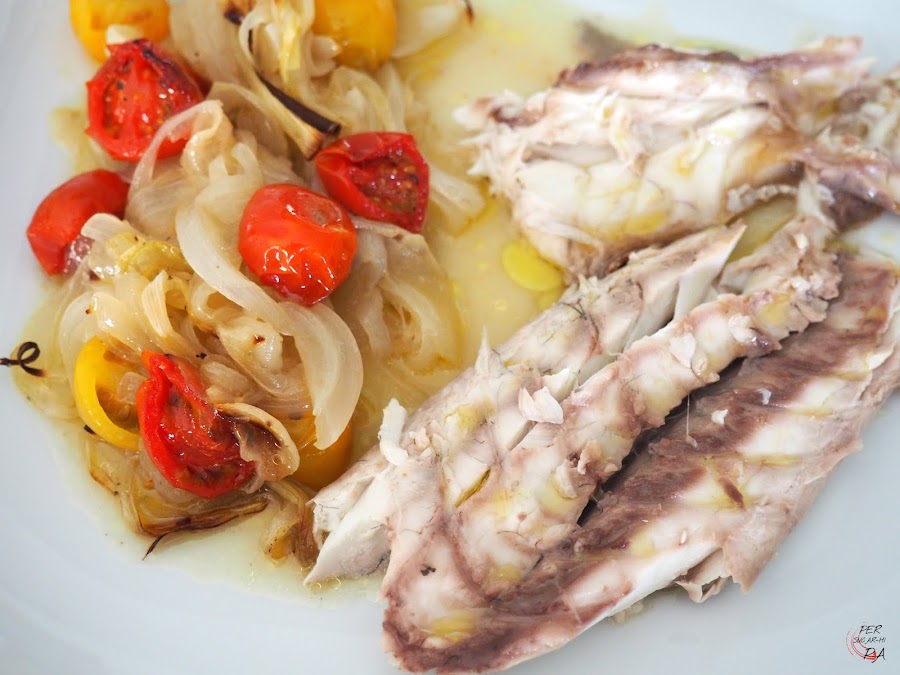 Corvina al horno con limón y guarnición de tomates cherrys y cebolla.