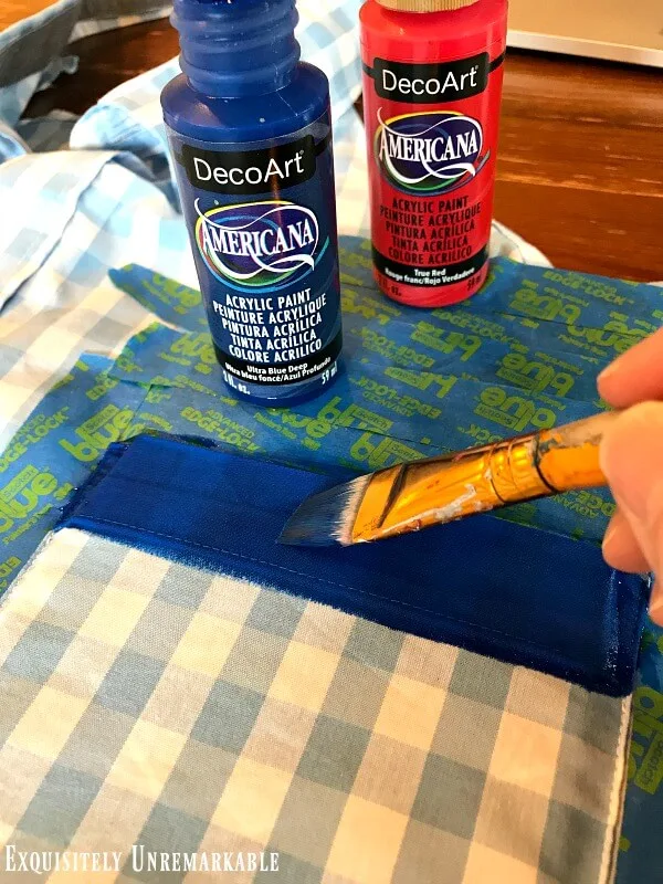 Painting a blue stripe on the pocked of a men's gingham shirt. 