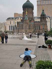 photographer and couple taking wedding photos next to the Saint Sophia Cathedral in Harbin