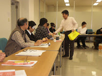 机をまわって参加者にモノをわたす広瀬さん