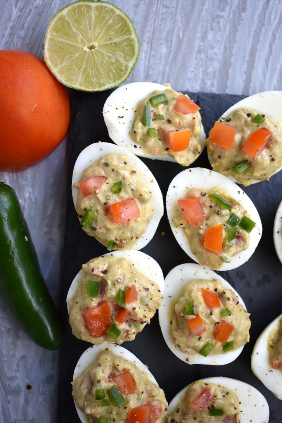 Guacamole Deviled Eggs is an awesome appetizer that features hard boiled egg whites filled with flavorful guacamole with jalapeno and tomatoes. www.nutritionistreviews.com
