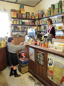 Full-scale model of the interior of a 1930s shop, with a shopkeeper serving a school boy in uniform.