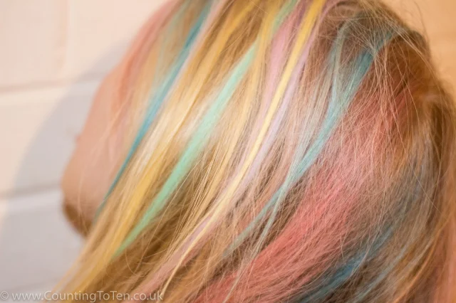 A view of the side of my daughter's blonde hair with streaks of different colours in it