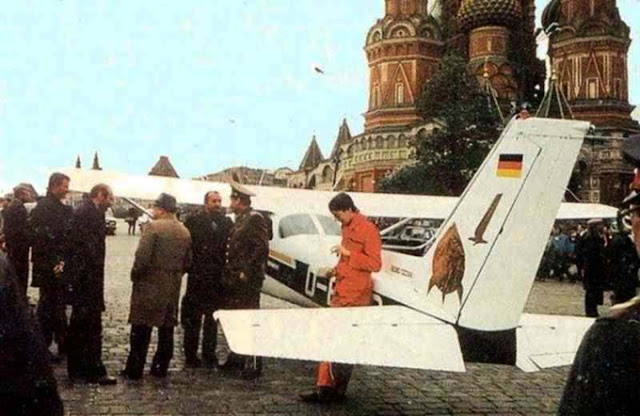 Rust's Cessna 172, resting near Red Square some time after his landing. Rust is standing on the right in the photo, wearing colored overalls.