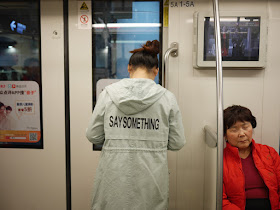 young woman wearing a jacket with "SAY SOMETHING" on the back