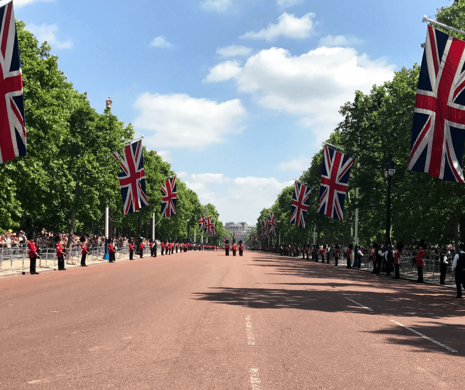 Queen's Guards parade, the road is lined with Union Jacks and the soldiers are walking towards the camera