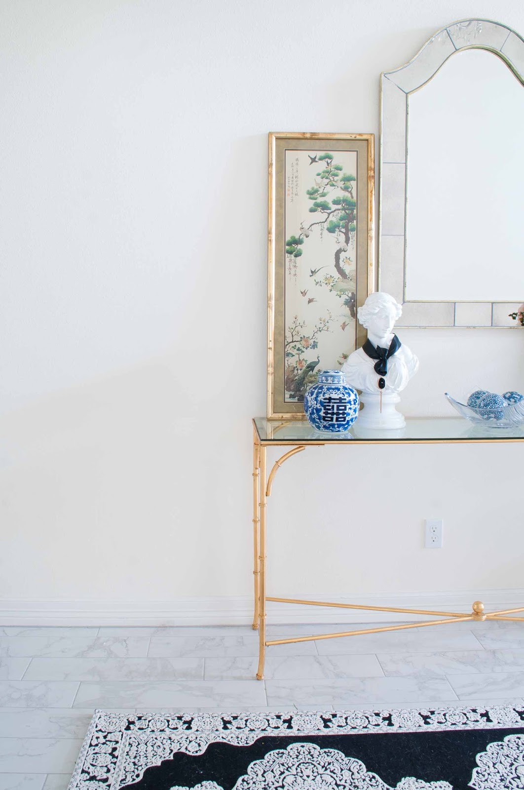 Gold console table with chinoiserie decor and black and white touches in a foyer. Gold console table with chinoiserie decor and black and white touches in a foyer.
