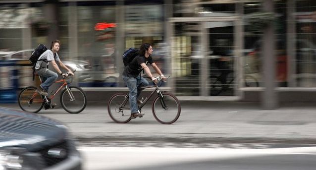 町中を自転車で移動する二人の若い男性。