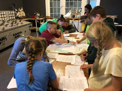 Students around a table with worksheets and other papers Students around a table with worksheets and other papers