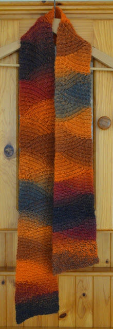 'Vesuvius' slip stitch scarf on a coathanger hanging on a pine dresser.