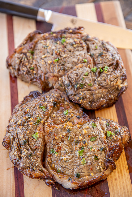 Air Fryer Ribeyes - so easy and taste fantastic!! Ready in minutes! We marinated the steaks in a simple Greek marinade of olive oil, lemon juice, garlic, oregano, salt, pepper and red pepper flakes. Marinate a few hours to overnight. Ready to eat in under 10 minutes! #steak #airfryer #steakmarinade Two Ribeye steaks cooked in the air fryer