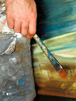Elinde fırçasıyla tablo önünde dikilen bir ressam